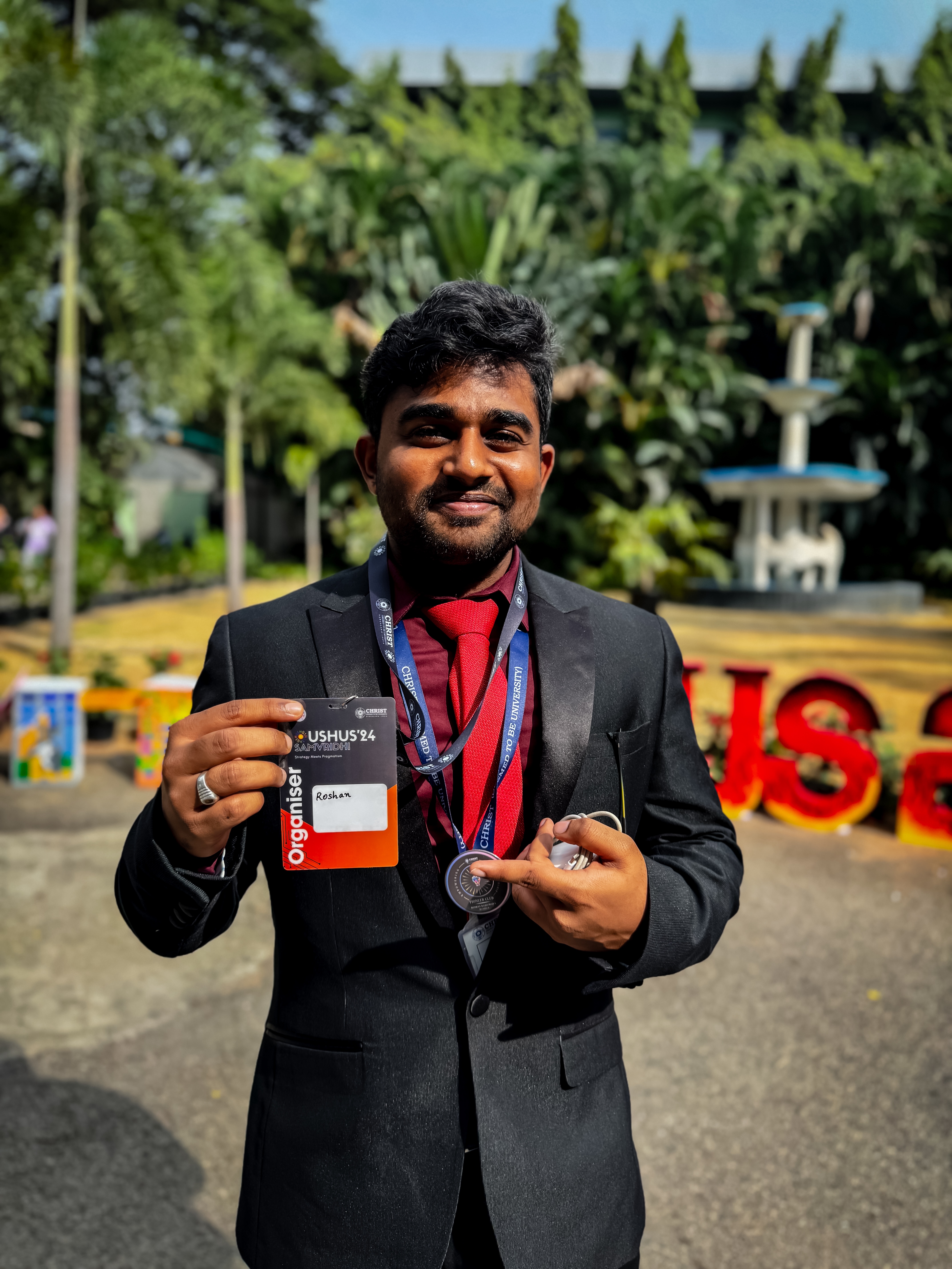 Roshan Rajkumar Sivakumar wearing USHUS 2024 event coordinator organiser badge and medal at Christ University Bengaluru national management festival