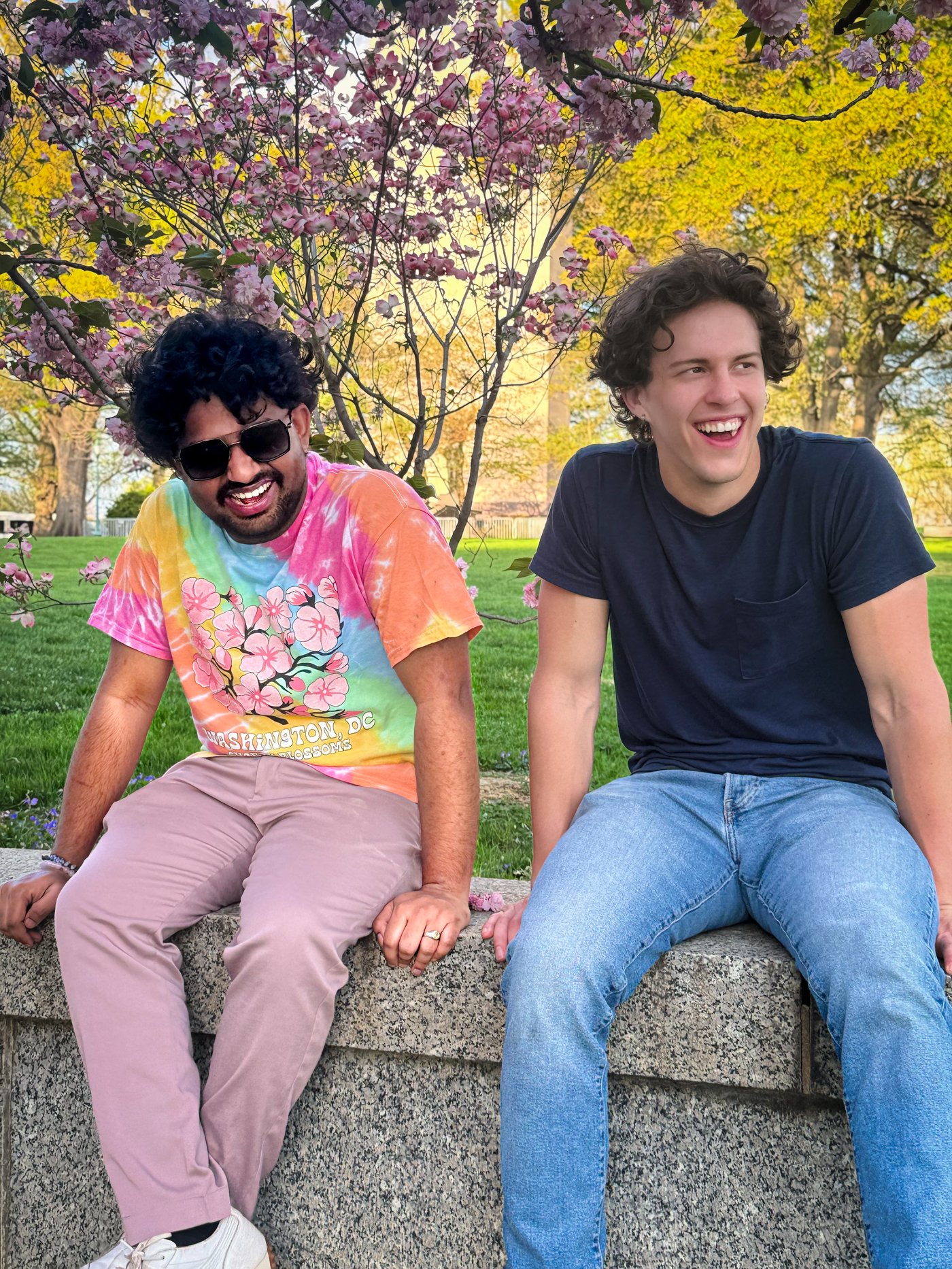 Roshan R Sivakumar and Rilee sitting under cherry blossom trees at Washington DC Mall, April 5 2026, wearing tie-dye cherry blossom shirt