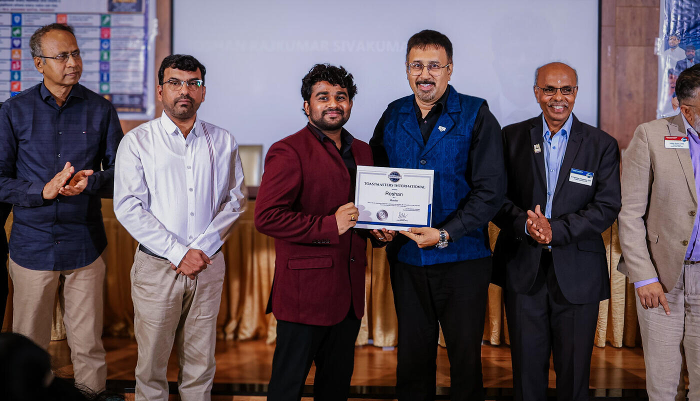 Roshan R Sivakumar receiving his membership certificate from Toastmasters International